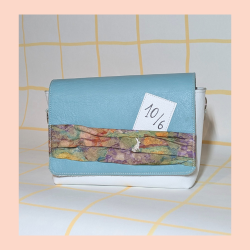 Godot-San maroquinerie rabat "chapelier fou" monté sur poche blanche. fond vert d'eau, empiècement tissus type foulard que l'on trouve sur le rebord du chapeau, carte 10/6 en cuir cousues et breloque lapin en métal.